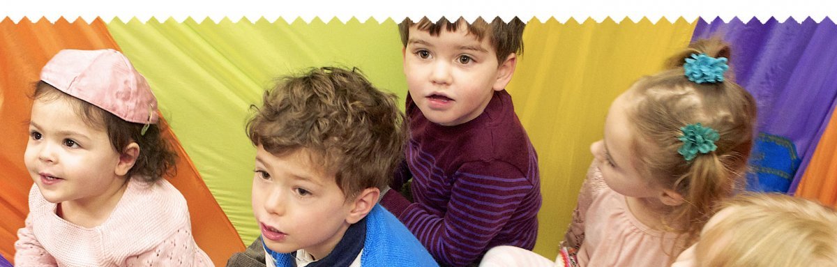 children at tot shabbat event, sitting on colorful parachute